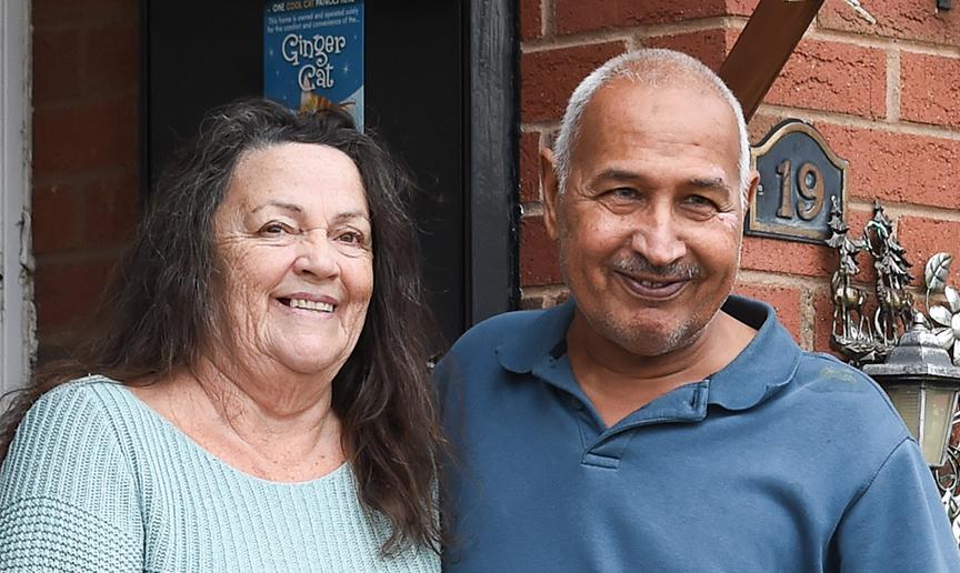 Two people smiling outside the front door of a house